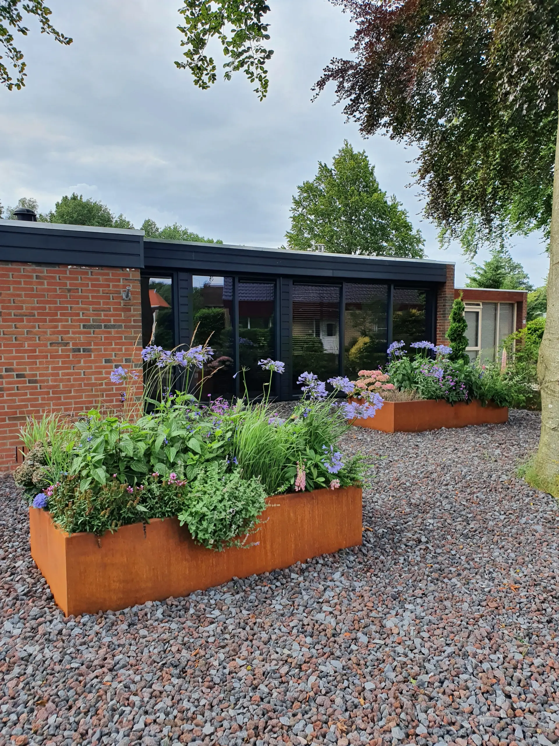 Grote cortenstaal plantenbak op maat geplaatst bij modern woonhuis