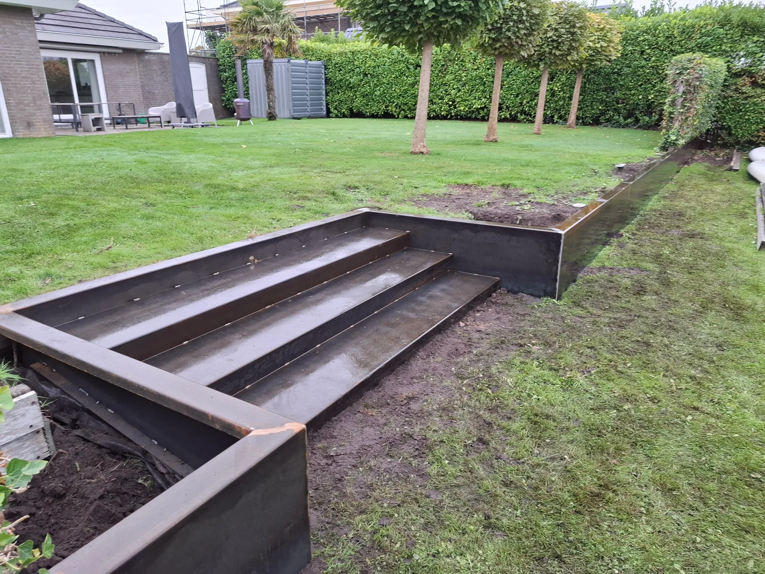 Maatwerk cortenstaal tuintrap verwerkt in gazon en glooiing