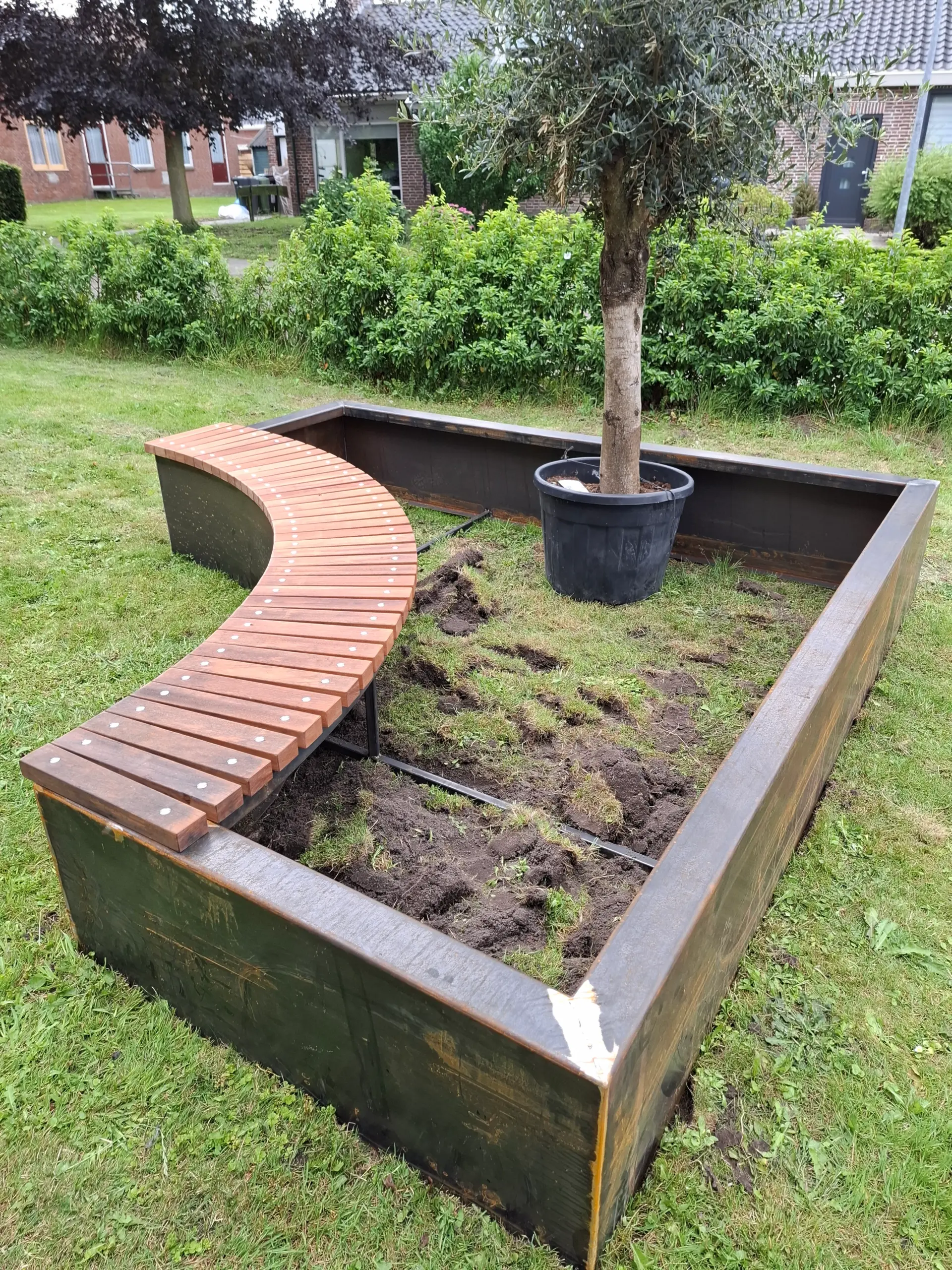 Gebogen cortenstaal plantenbak gecombineerd met geïntegreerde houten zitbank